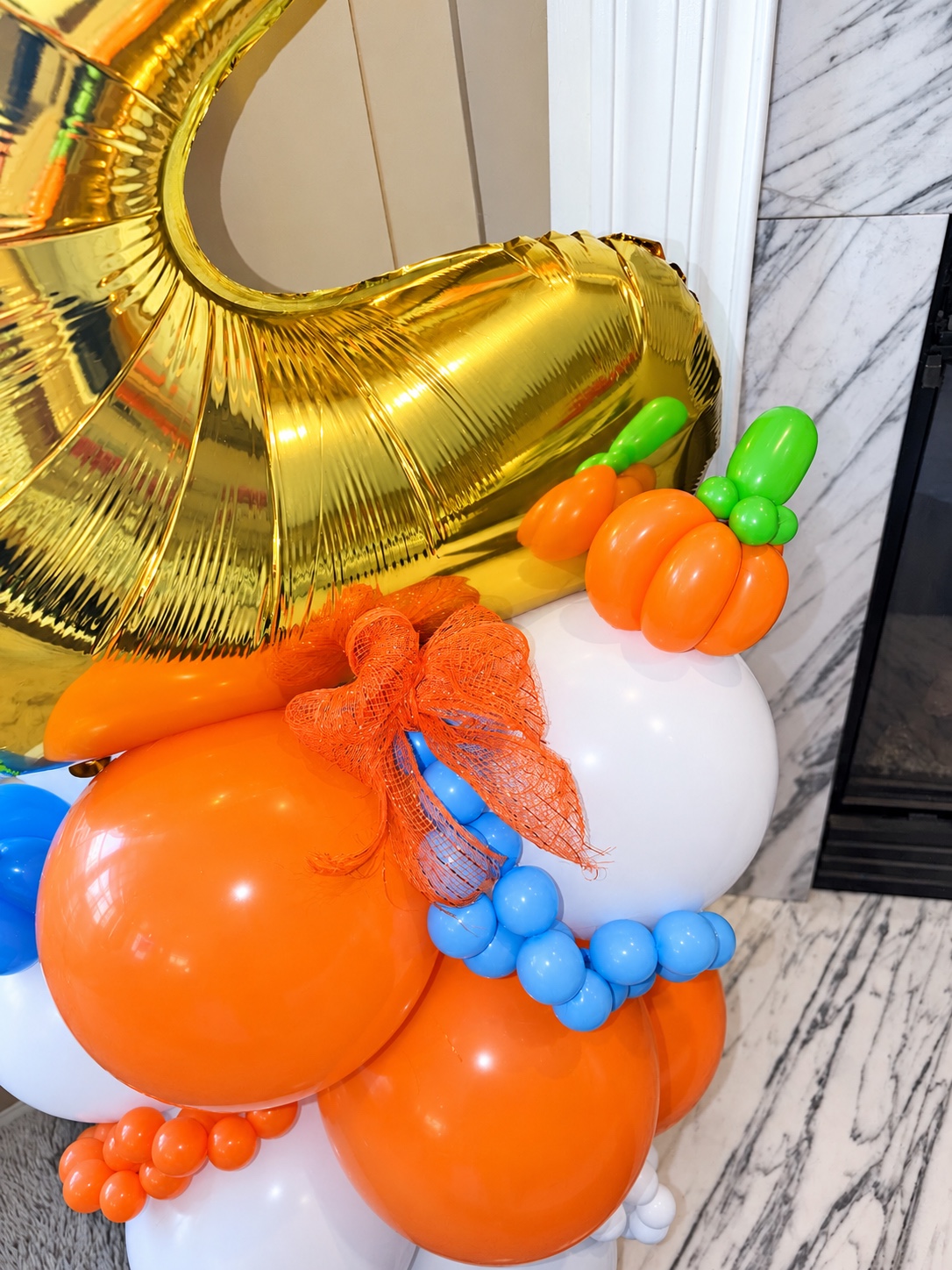 Detailed view of the handmade balloon pumpkin and orange bow on a fall-themed balloon stack
