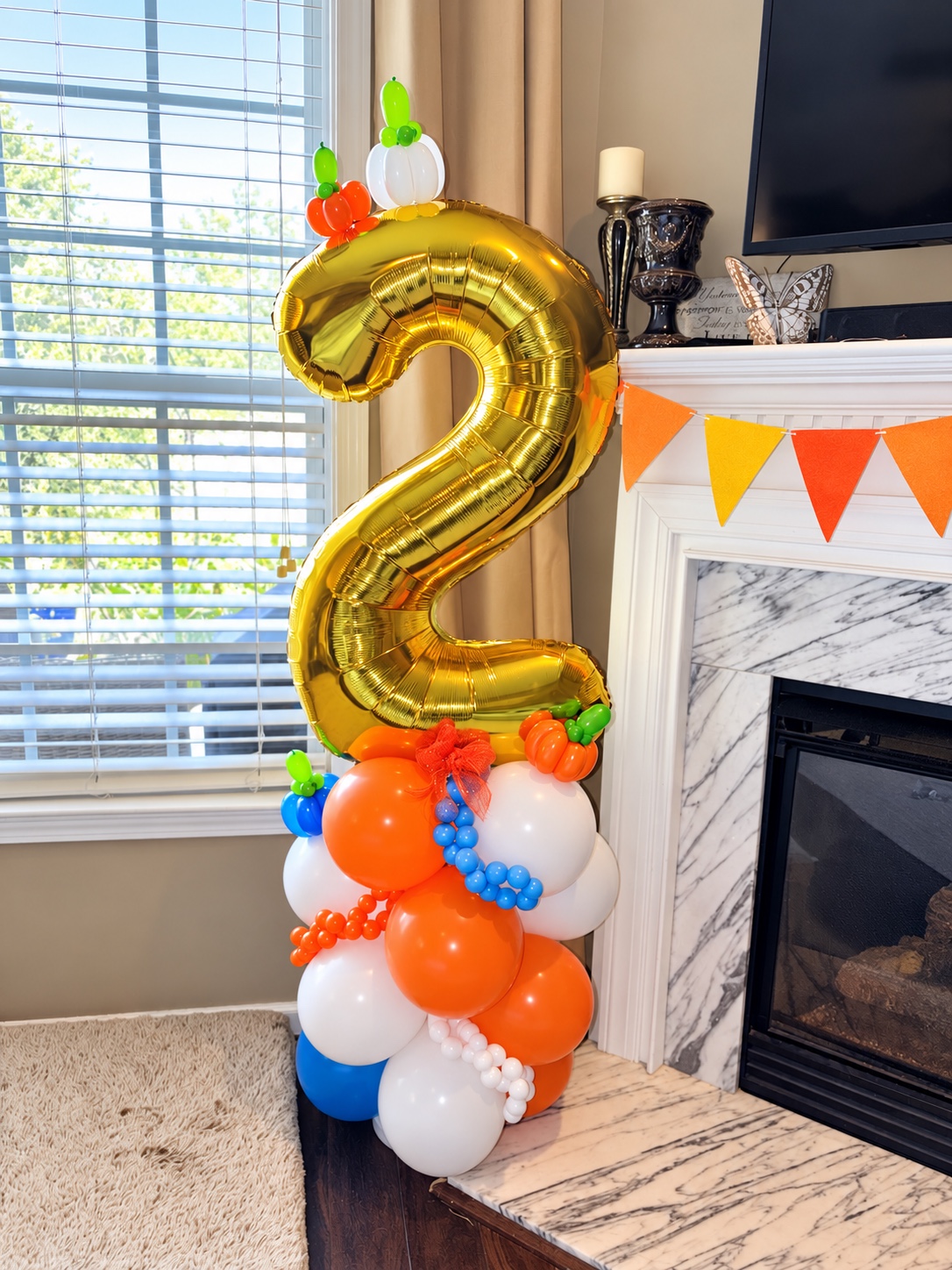 Fall-themed gold number two balloon stack with orange, blue, green, and white balloons
