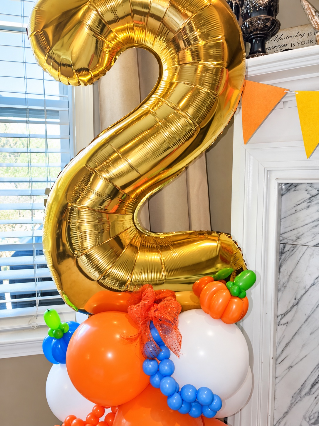 Close-up of a fall-themed gold number two balloon stack with pumpkins and an orange bow